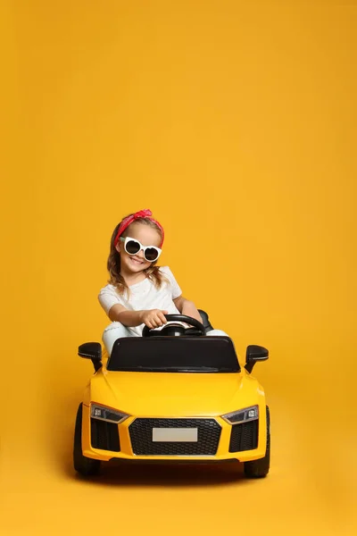Aranyos Kislány Vezetés Gyerekek Elektromos Játék Autó Sárga Háttér — Stock Fotó