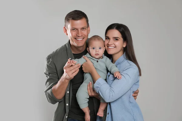 Família Feliz Casal Com Seu Bebê Bonito Fundo Cinza — Fotografia de Stock