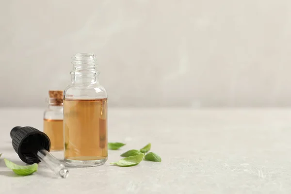 Bottles Essential Basil Oil Fresh Leaves Light Grey Table Space — Stock Photo, Image