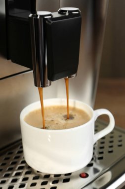 Modern espresso makinesi, fincana kahve dolduruyor, ahşap arka planda, yakın plan