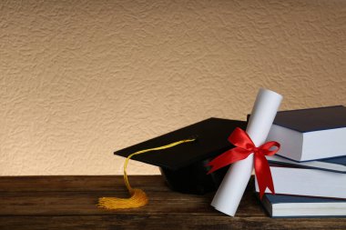 Mezuniyet şapkası, kitaplar ve diploma tahta masada. Metin için boşluk