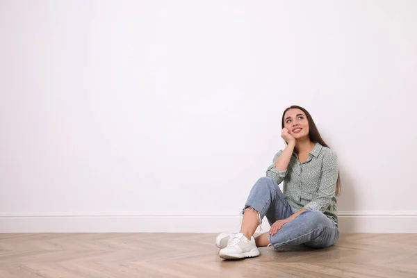 若い女性の床に白い壁の近くに屋内に座っている テキストのスペース — ストック写真