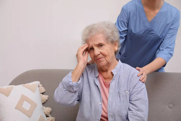 Pielęgniarka Zajmująca Się Starszą Kobietą Bólem Głowy Pomieszczeniach — Zdjęcie stockowe