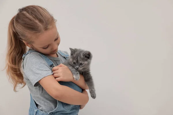 可爱的小女孩带着小猫在浅色的背景上 文字的空间 幼小的宠物 — 图库照片