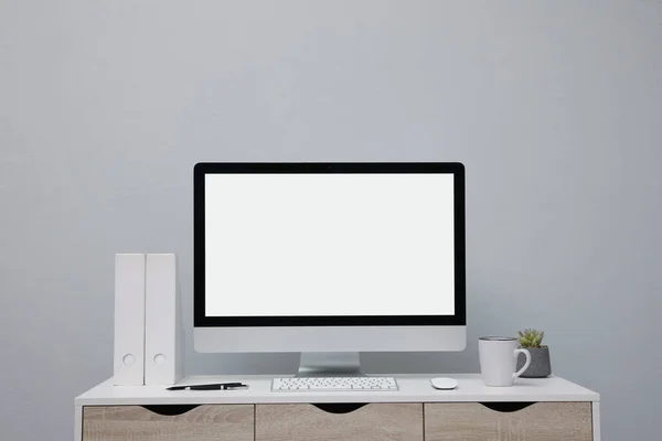 舒适的工作环境 在明亮的灰色墙壁附近的桌子上有空白的计算机显示 案文的篇幅 — 图库照片