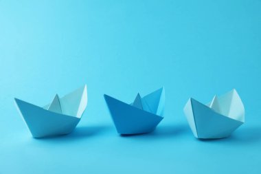 Açık mavi arka planda el yapımı kağıt tekneler. Origami sanatı