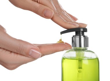 Beyaz arkaplanda sıvı sabun makinesi kullanan kadın, yakın plan.