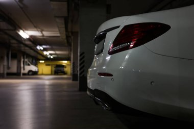 White car in parking garage, closeup. Space for text clipart