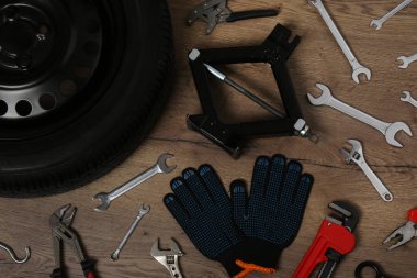 Araba tekerleği, makas kriko, eldivenler ve tahta yüzeyde farklı aletler, düz yatış