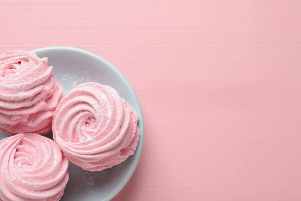 Plate with delicious zephyrs on pink table, top view. Space for text