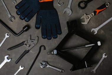 Araba makası kriko, eldivenler ve gri yüzeyde farklı aletler, düz yatıyordu.