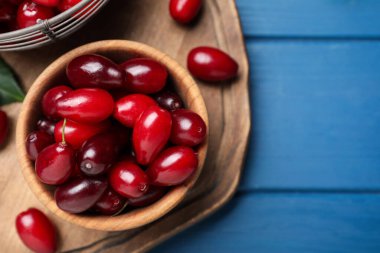 Mavi ahşap masada taze olgun kızılcık meyveleri, düz yerde. Metin için boşluk