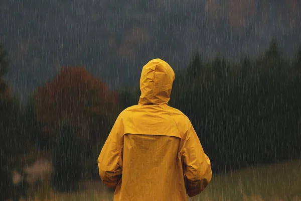 雨の下で山の風景を楽しむレインコートの女性は バックビュー — ストック写真