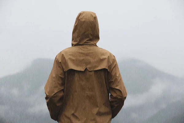 雨の下で山の風景を楽しむレインコートの女性は バックビュー — ストック写真