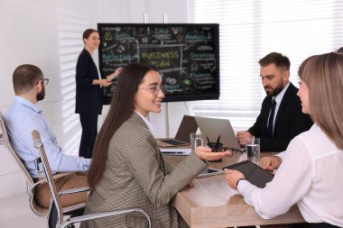 Sunum sırasında toplantı odasındaki etkileşimli yönetim kurulunun yanındaki işletme eğitmeni, meslektaşlarına odaklan