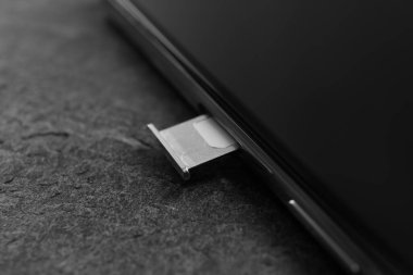Gri masadaki Sim kartlı cep telefonu, yakın plan.