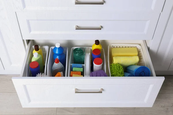 Different cleaning supplies in open drawer indoors