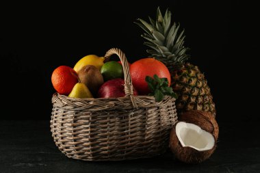 Taze olgun meyveler ve sepet siyah masada.