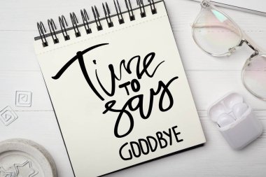 Deyimi olan bir defter Elveda deme zamanı, gözlükler ve kulaklıklar beyaz ahşap masada, düz yatıyordu