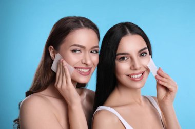 Açık mavi arka planda eşleşen mendil kullanan güzel kadınlar