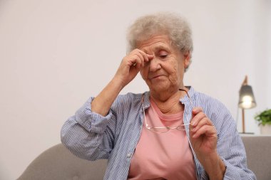 Evde kanepede oturan baş ağrısı olan son sınıf öğrencisi kadın.