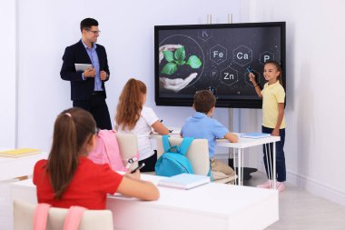 Öğretmen ve öğrenci ders sırasında sınıfta etkileşimli pano kullanıyor