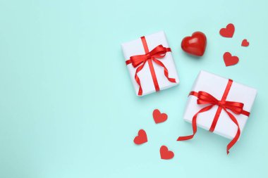 Turkuaz arka planda dekoratif kırmızı kalpleri olan hediye kutuları, düz yatış. Metin için boşluk