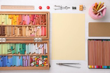 Boş kağıt, yumuşak pasteller ve sanatçının işyerindeki beyaz ahşap masaya çizim malzemeleri, üst manzara. Tasarım için boşluk