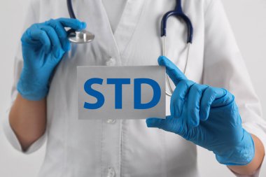 Beyaz arka planda STD kısaltması olan kağıt tutucu doktor, yakın plan.