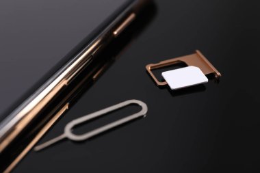 SIM kart, akıllı telefon ve fırlatıcı siyah arkaplanda, yakın plan