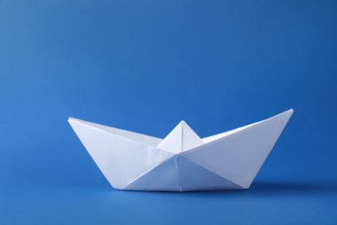 Mavi arka planda el yapımı beyaz kağıt tekne. Origami sanatı