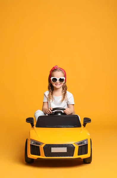 Cute Little Girl Driving Children Electric Toy Car Yellow Background — Stock Photo, Image