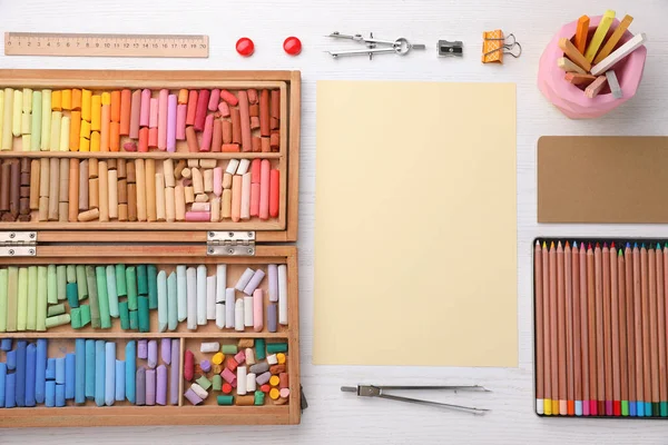 Boş kağıt, yumuşak pasteller ve sanatçının işyerindeki beyaz ahşap masaya çizim malzemeleri, üst manzara. Tasarım için boşluk