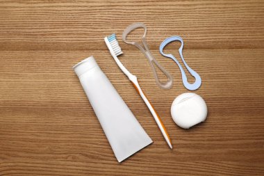 Dil temizleyici ve diş bakımı ürünleriyle ahşap masa üzerinde düz kompozisyon