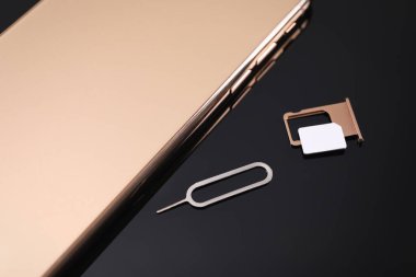 Siyah arkaplanda SIM kart, akıllı telefon ve fırlatıcı, üst görünümde