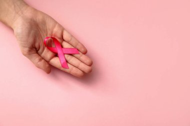 Renkli arka planda pembe kurdele tutan kadın, yazı için yeri olan üst manzara. Göğüs kanseri farkındalığı konsepti