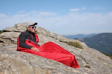 Dağ zirvesinde uyku tulumunda bir turist