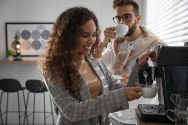Afrika kökenli Amerikalı kadın modern makineyle taze aromatik kahve hazırlıyor.