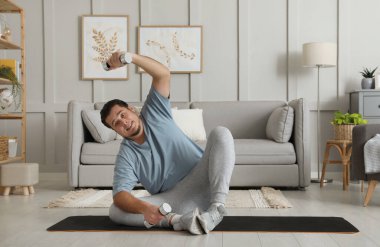 Kilolu adam evde halterli egzersiz yapıyor.