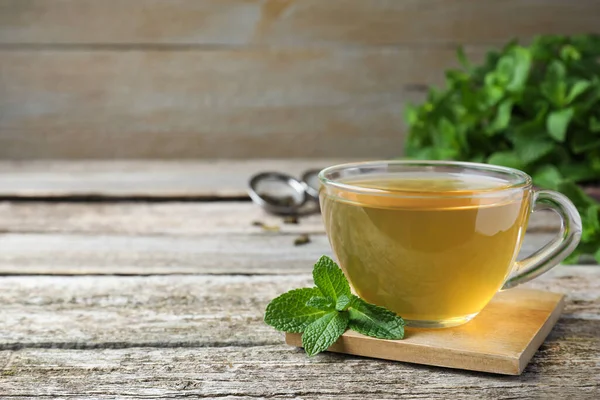 Tahta masada bir fincan sıcak aromatik nane çayı. Metin için boşluk