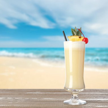 Lezzetli Pina Colada kokteyli okyanusun yanındaki ahşap masada. Metin için boşluk