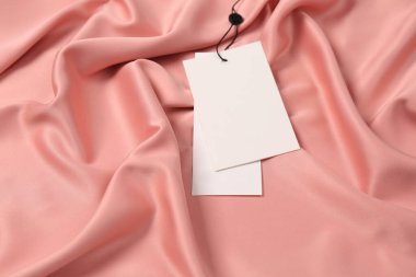 Pembe ipeksi kumaş üzerinde boş beyaz etiketler. Metin için boşluk