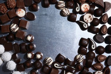 Metal yüzeyde farklı lezzetli çikolata şekerlerinden yapılmış bir çerçeve. Metin için boşluk