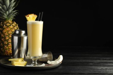 Lezzetli Pina Colada kokteyli ve siyah ahşap masa malzemeleri, metin için yer.