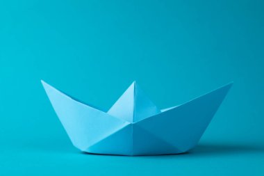 Açık mavi arka planda el yapımı kağıt tekne. Origami sanatı