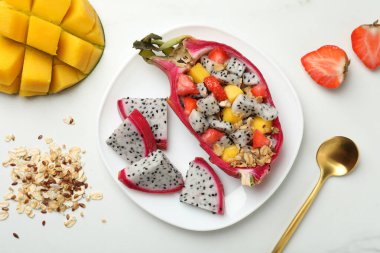 Mango, granola ve çilekli nefis pitahaya teknesi beyaz masada, düz yatıyordu.