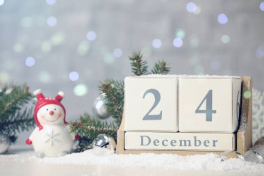 24 Aralık - Noel arifesi. Tahta blok takvimi ve bulanık ışıklara karşı karda şenlikli dekor