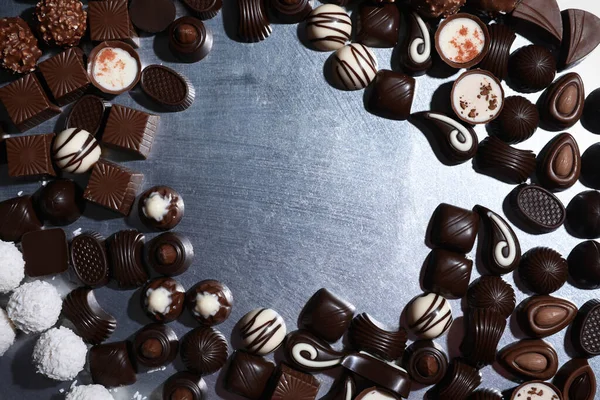 Metal yüzeyde farklı lezzetli çikolata şekerlerinden yapılmış bir çerçeve. Metin için boşluk