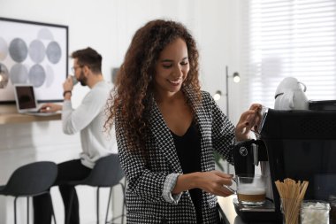 Afrika kökenli Amerikalı kadın modern makineyle taze aromatik kahve hazırlıyor.