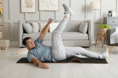 Kilolu adam evde halterli egzersiz yapıyor.